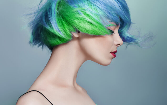 Portrait Of A Woman With Bright Colored Flying Hair, All Shades Of Blue Purple. Hair Coloring, Beautiful Lips And Makeup. Hair Fluttering In The Wind. Sexy Girl With Short Hair. Professional Coloring